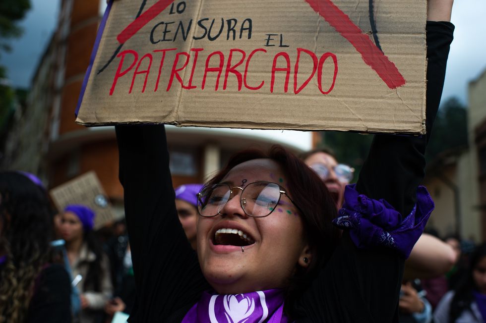 An image of a woman, holding a sign that says "Lo Censura El Patriarcado", participating in a demonstration in Bogota for International Women's Day