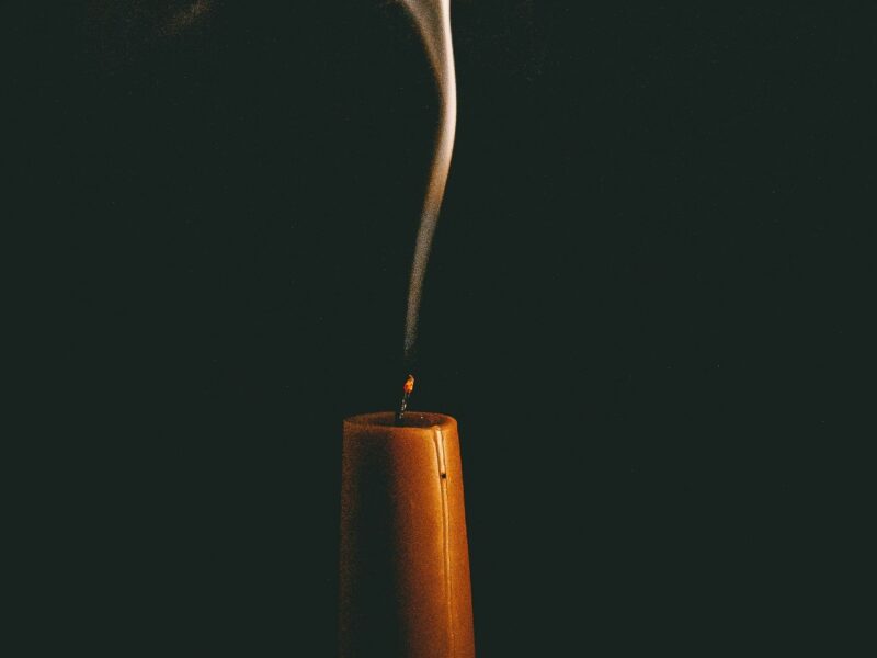 An image of an orange candle burning, with smoke on top of it.