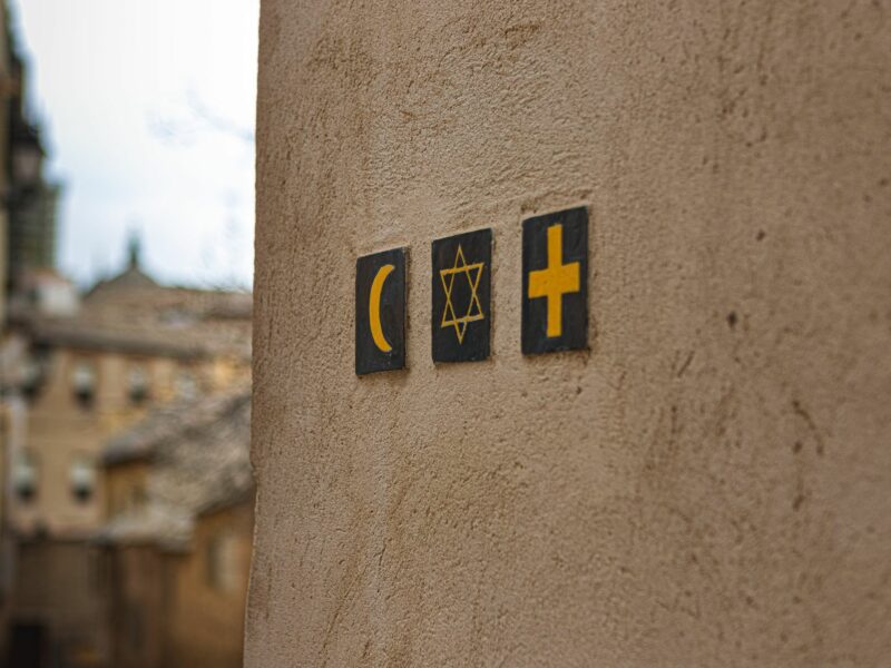 An image of three religious signs (Islam, Judaism and Christianity) on a wall in a street outside.