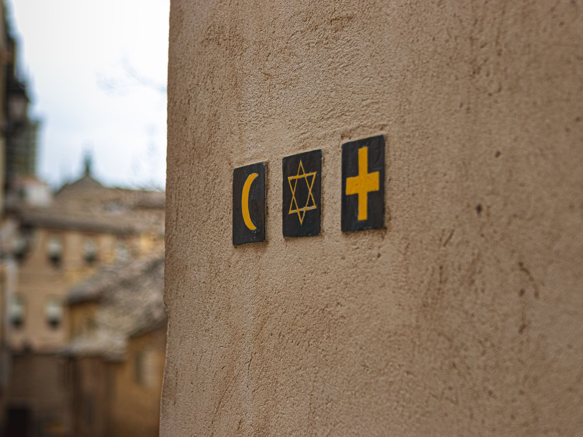 An image of three religious signs (Islam, Judaism and Christianity) on a wall in a street outside.