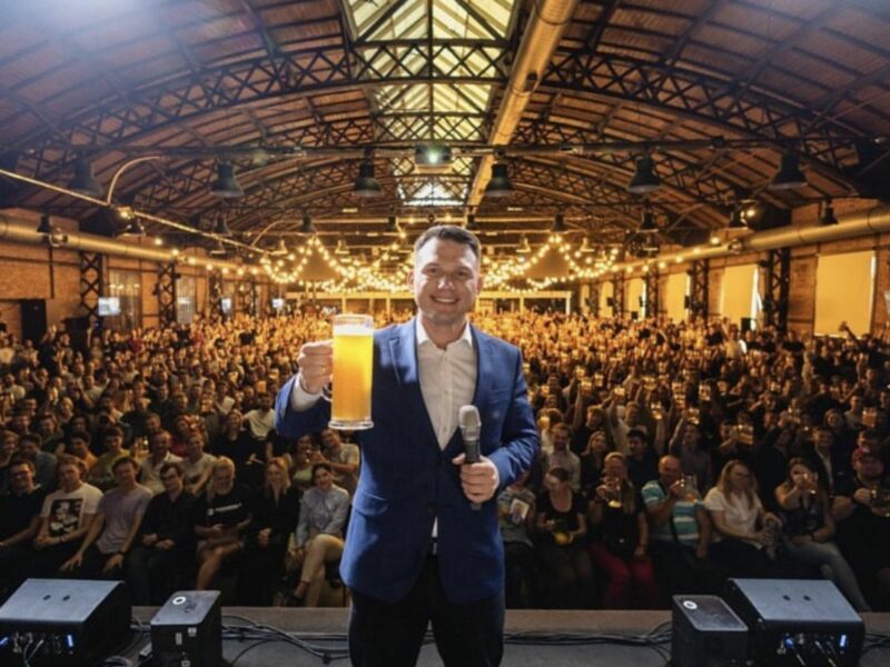 an image showing Sławomir Mentzen at one of his campaign events where he has beers with the audience.