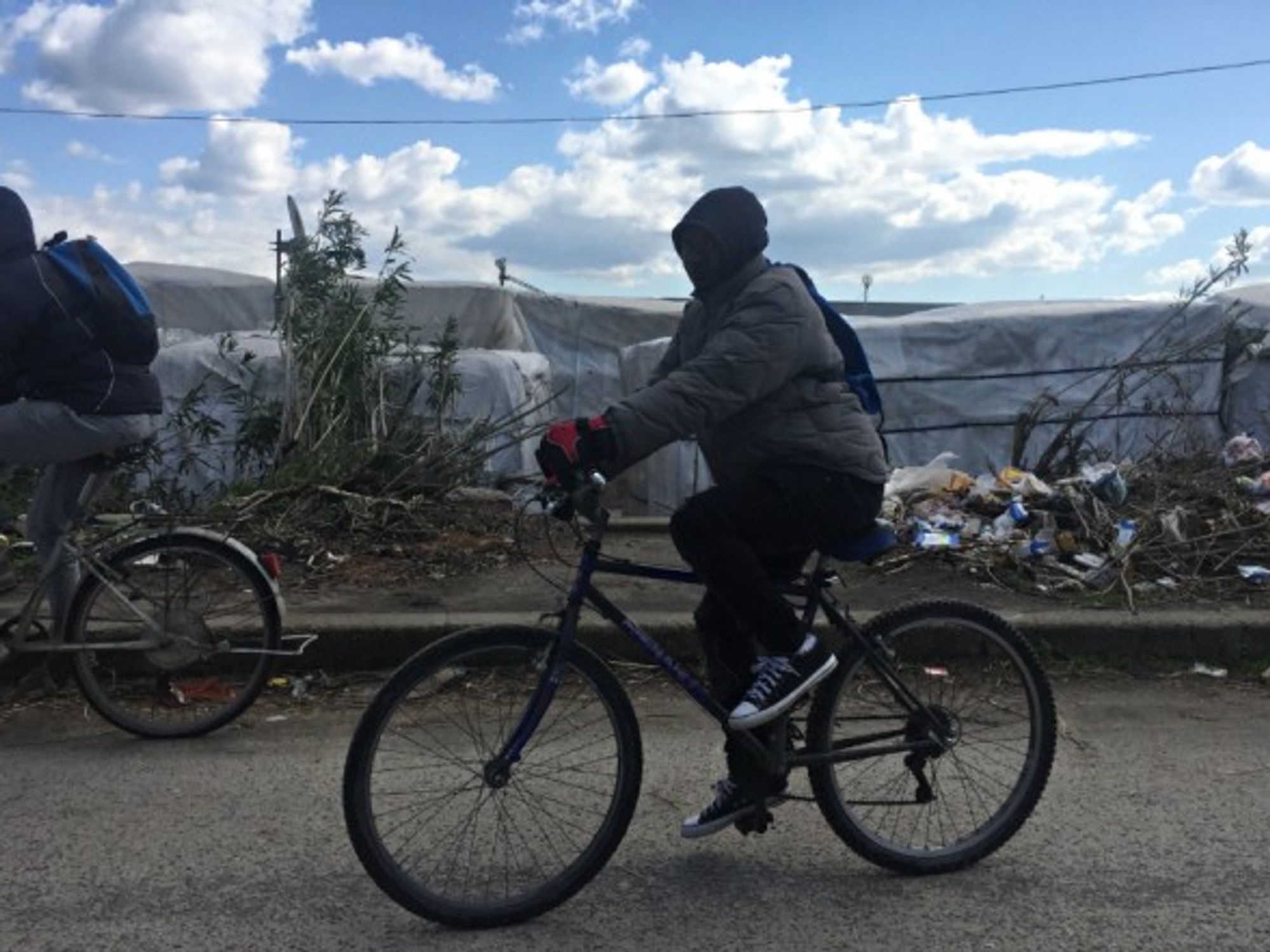 An immigrant rides a bike along a shantytown in San Ferdinando, Italy