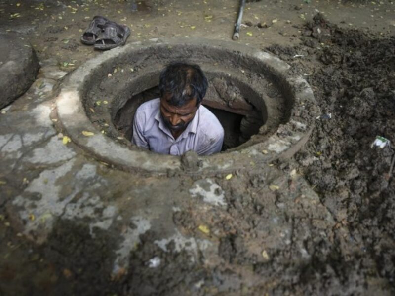 An Indian manual scavenger cleans a manhole in New Delhi in August 2018