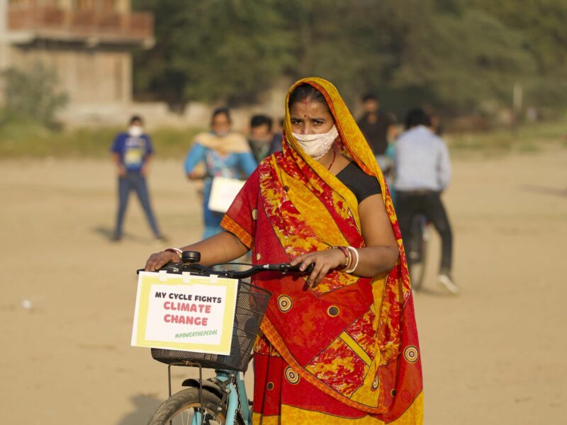 An Indian woman pushing a bike.