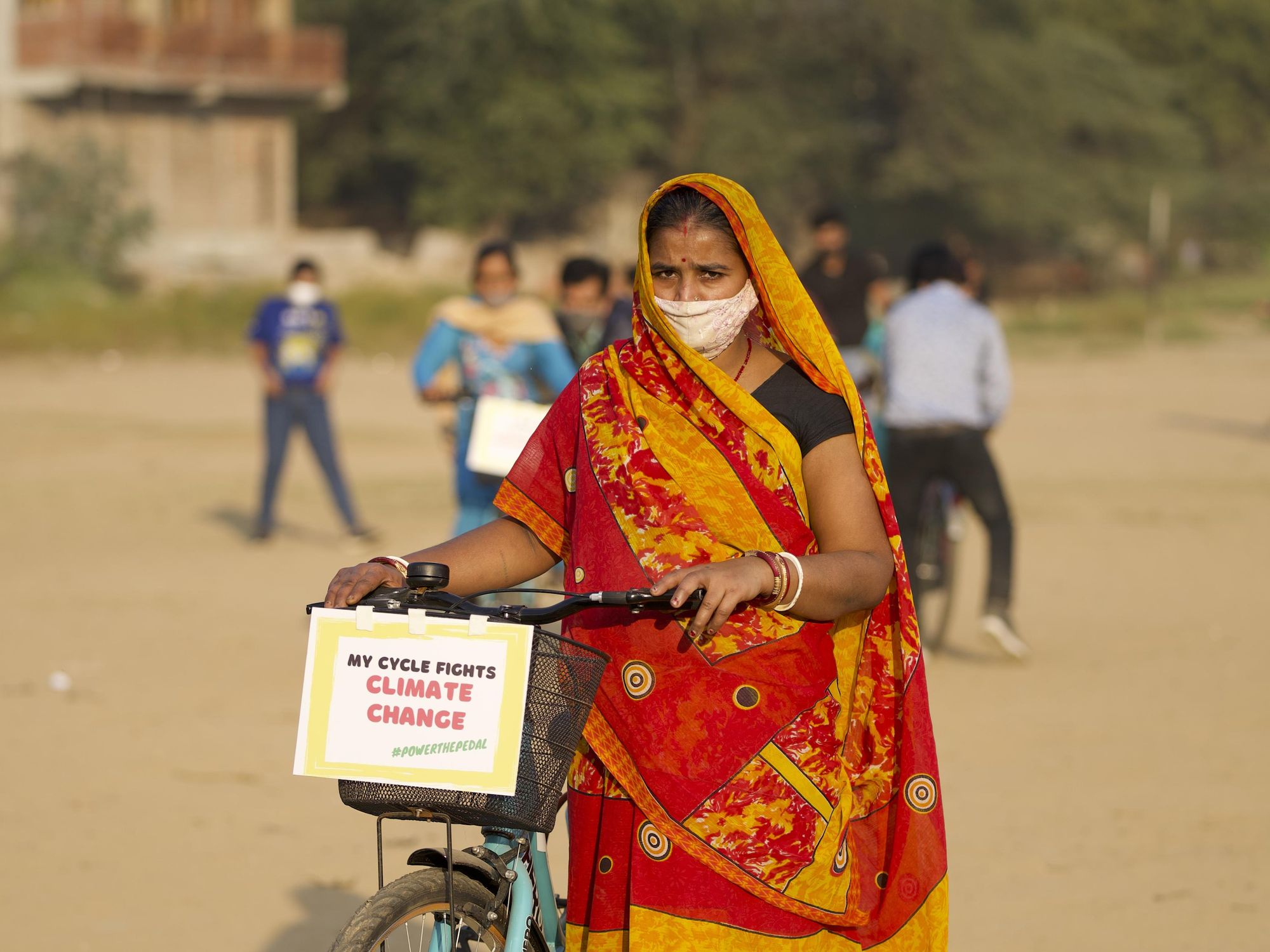 An Indian woman pushing a bike.
