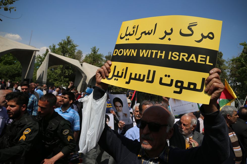 An Iranian man carries a placard written ''DOWN WITH ISRAEL'' in front of the main entrance of Tehran University during an anti-Israel rally in Tehran.