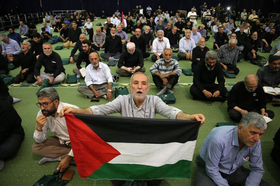 An Iranian man holds a Palestine flag during a memorial ceremony for the slain head of the Hamas political bureau, Ismail Haniyeh (portrait top), at the Mosallah mosque in Tehran.