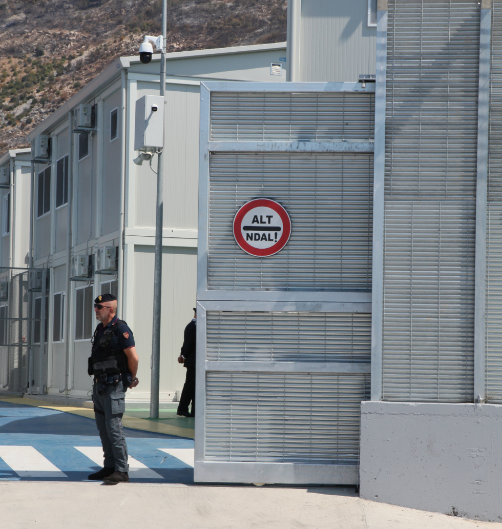 An Italian police officer stands at the entrance to the Italian arrival camp for refugees in the port city of Shengjin in northern Albania.