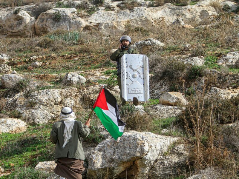 An old Palestinian protester waves Palestinian flag while he confronts the Israeli soldiers during the demonstration against Israeli settlements in the village of Beit Dajan near the West Bank city of Nablus.