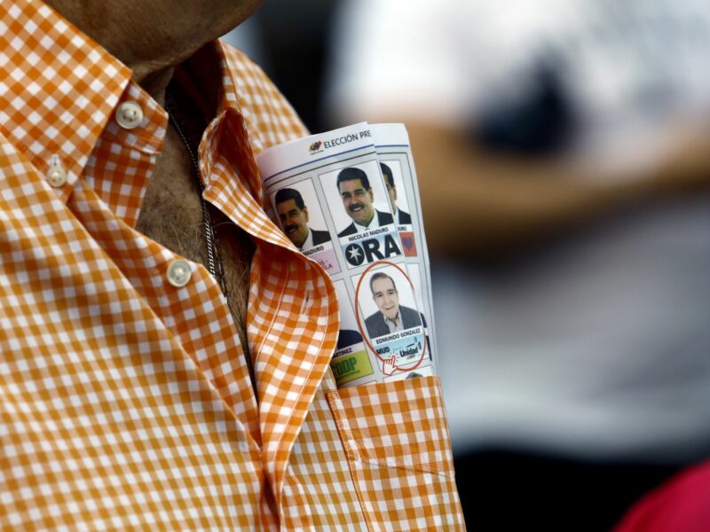 An opponent carries a voting guide showing the two main candidates of the Venezuelan elections, Nicolas Maduro and Edmundo Gonzalez.