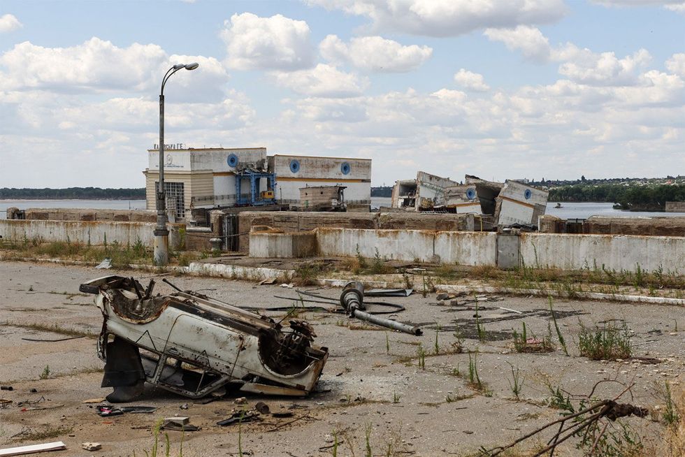 An overturned four by four sits outside a destroyed building near the reservoir.
