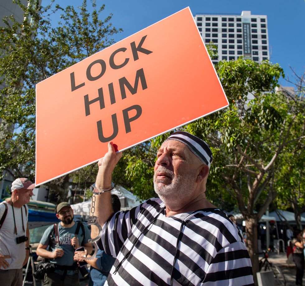 Anti-Trump protester holds sign asking that Donald Trump be jailed.