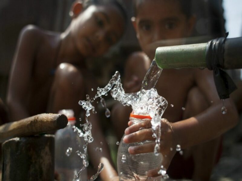 Bangladeshi children taking a bath by collecting supply water beside a road in Dhaka