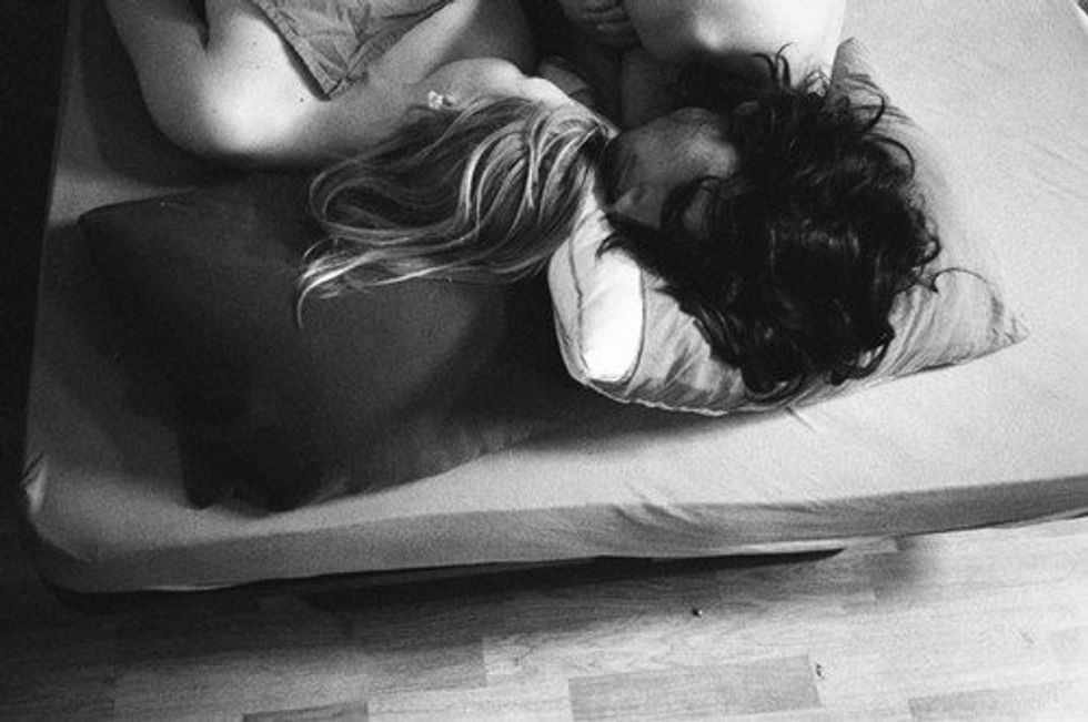 Black and white image of a couple sleeping in a bed.