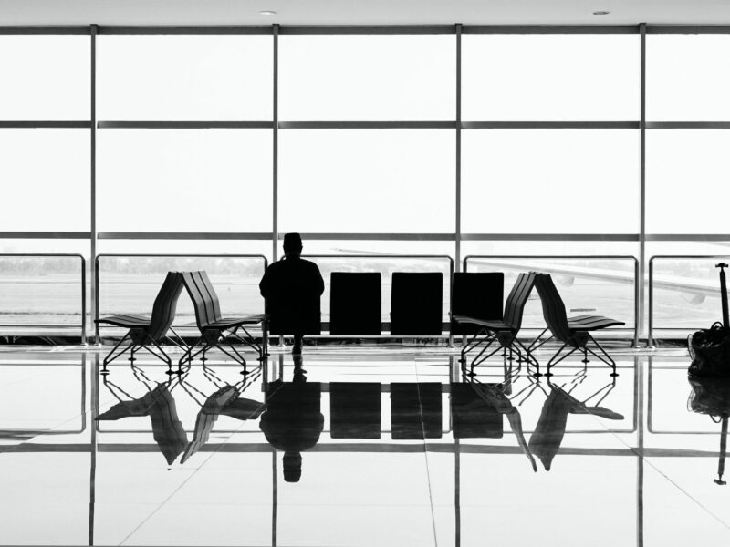 Black-and-white photo of a person sitting in an empty airport