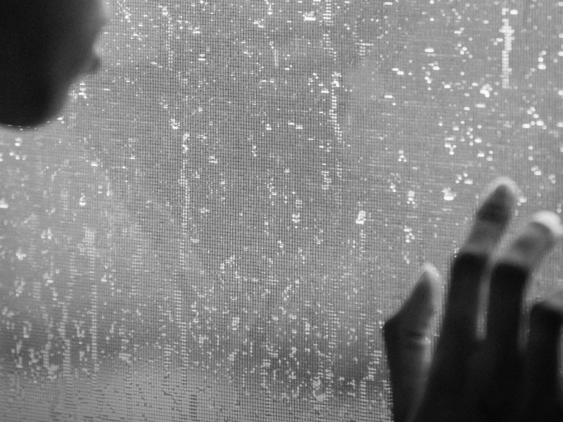 Black-and-white photo of a woman looking out a window