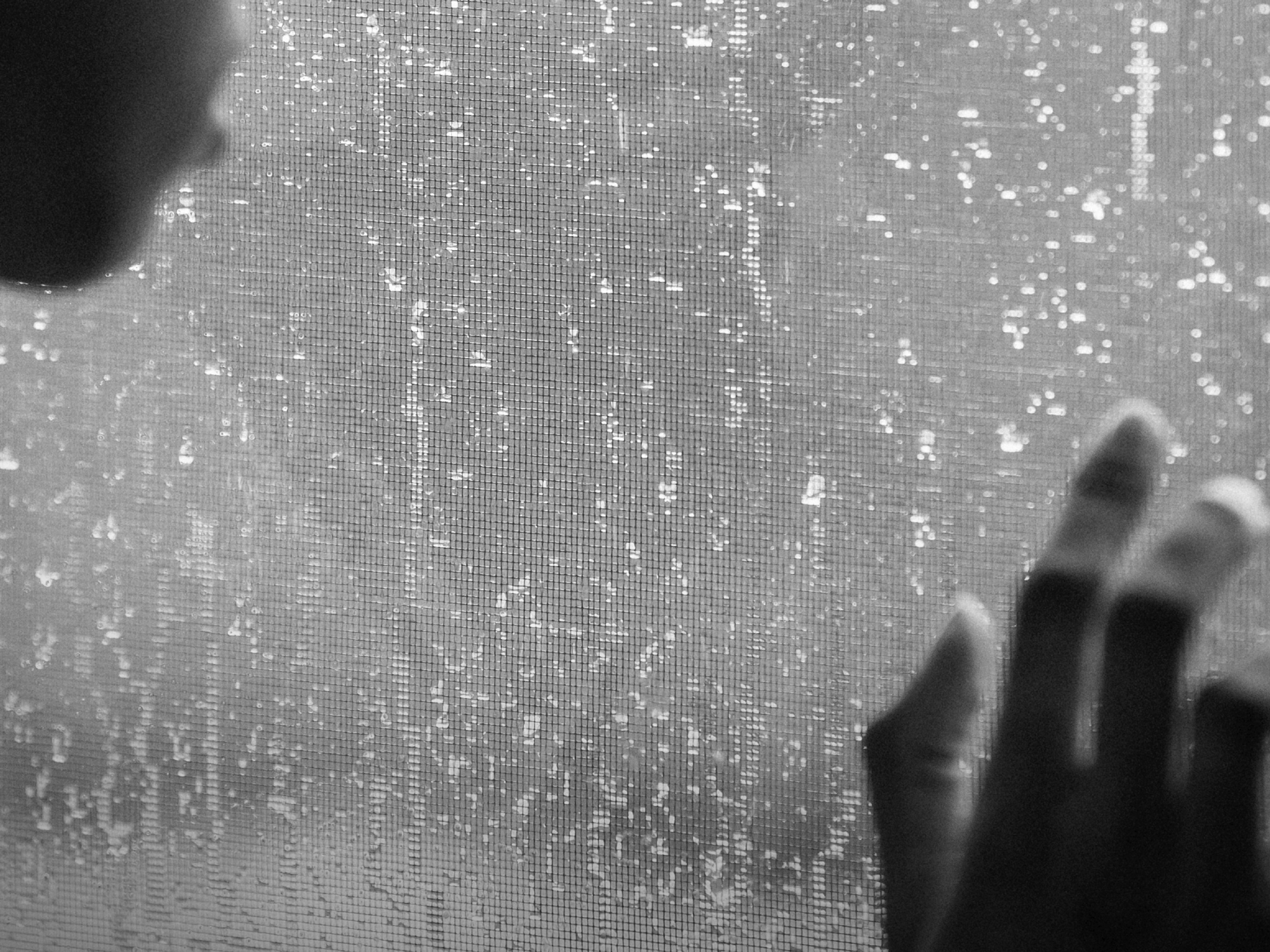 Black-and-white photo of a woman looking out a window