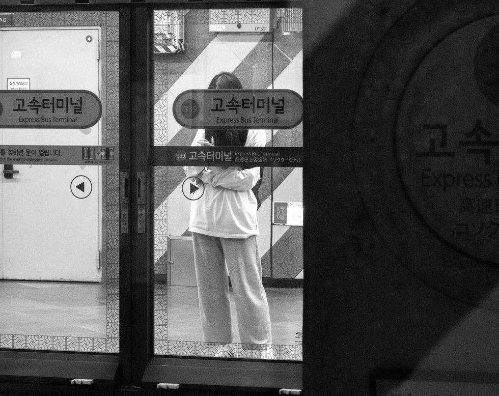 Black and white photo of a woman waiting for the metro in Seoul