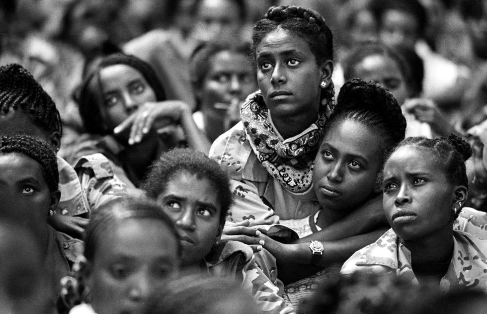 Black and white photo of Eritrean women soldiers looking up while attending an AIDS awareness lecture at a military base