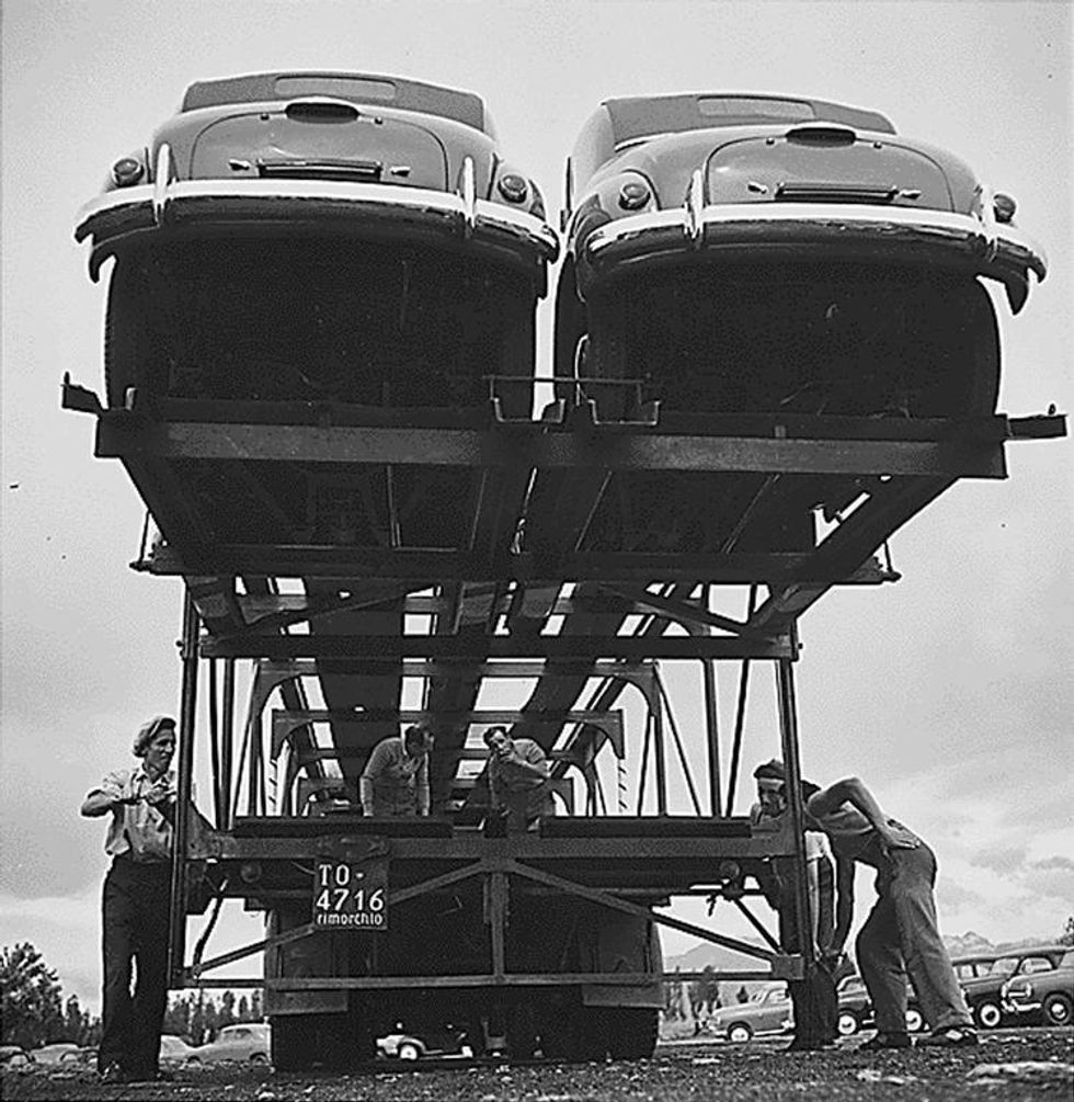 Black-and-white photo of Italian workers next to a truck carrying