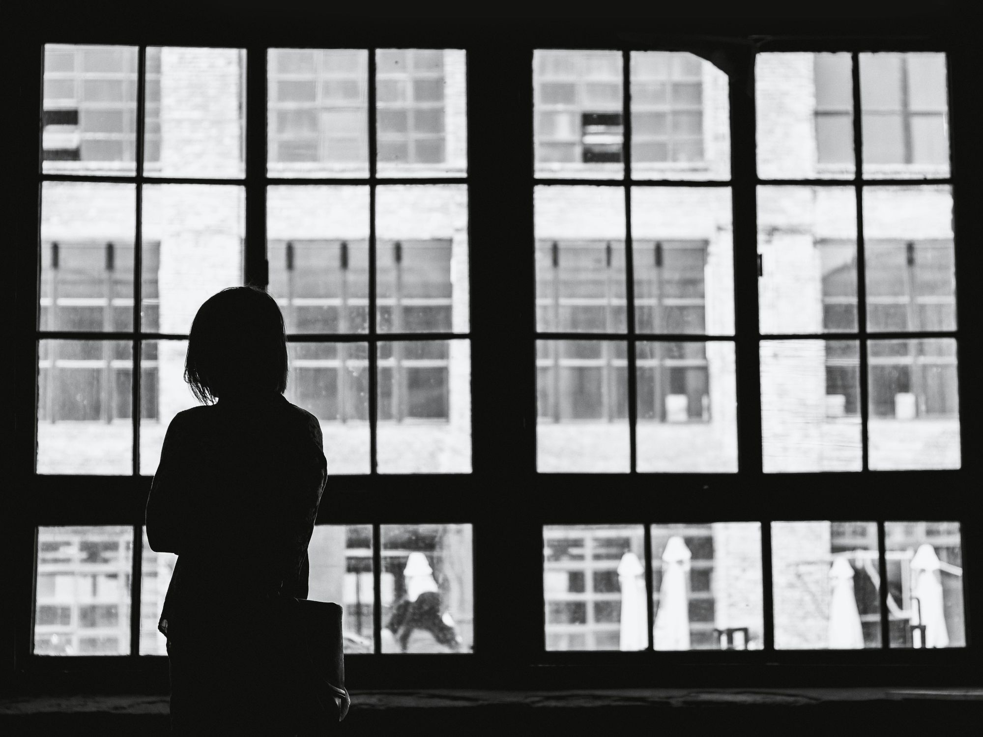 Black and white photo showing someone looking by the widow
