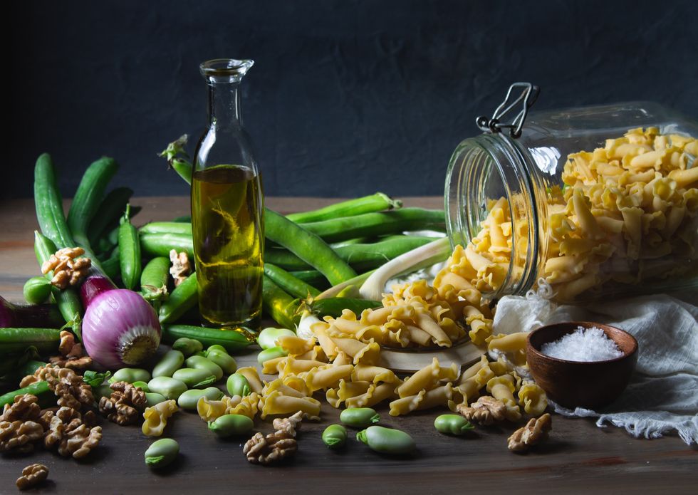 Bottle of olive oil surrounded by various ingredients.