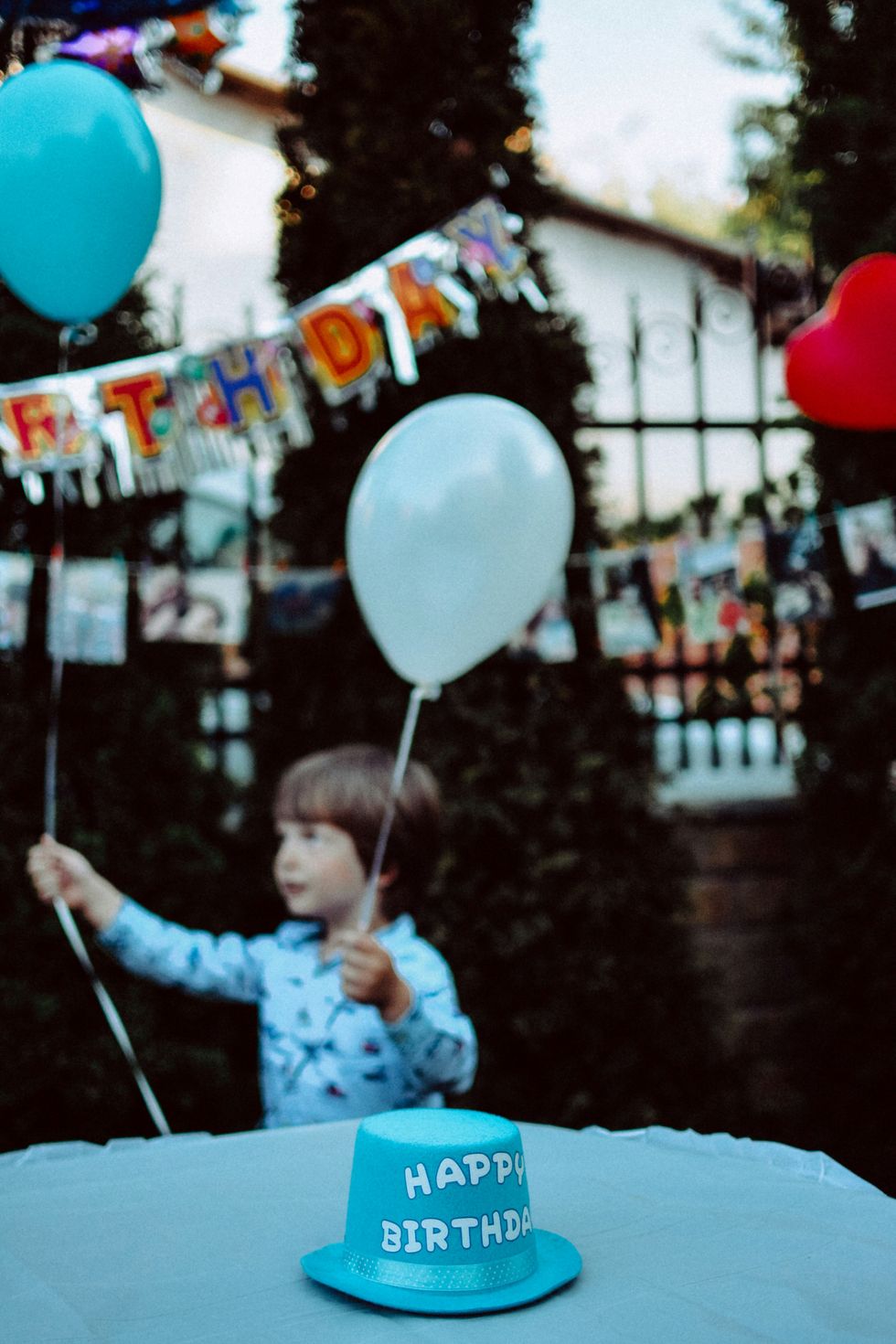 Boy holding blue and white balloons at a birthday party.