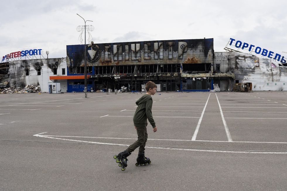 Boy in front of destroyed shopping center in Bucha
