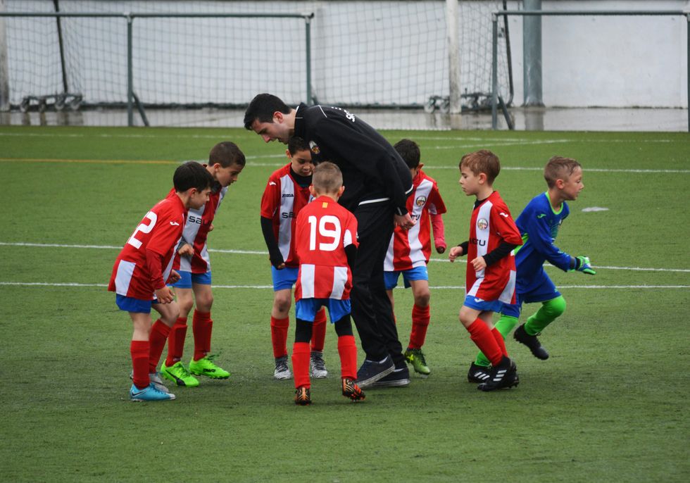 Children learn to play soccer with their coach in Spain