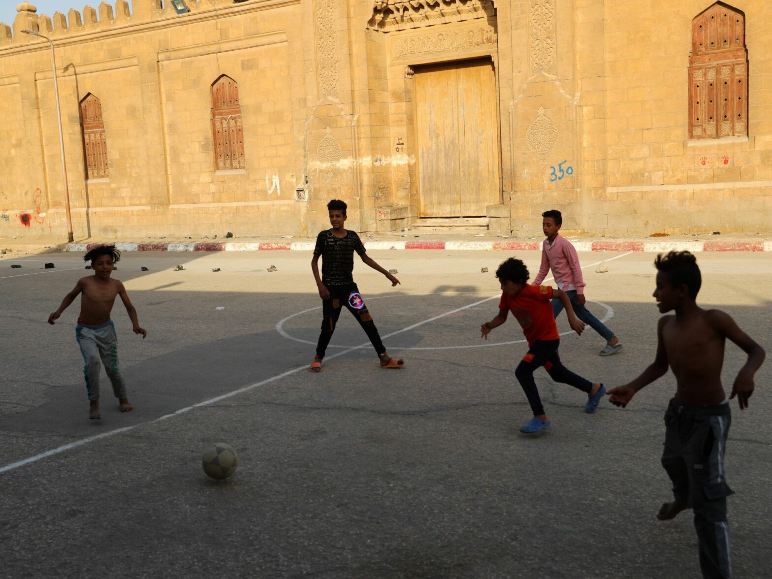 Children play football on an open space at a slum area with cemeteries