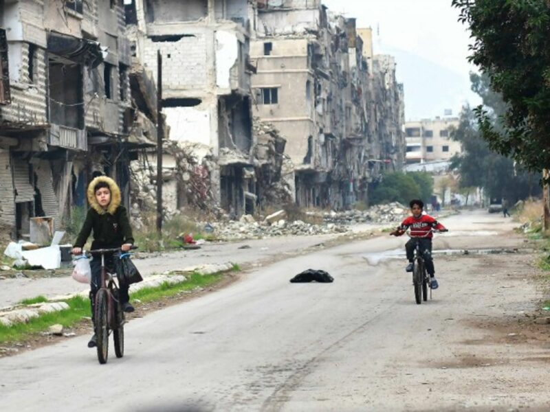 Children ride in the Yarmouk Camp area, south of the capital Damascus