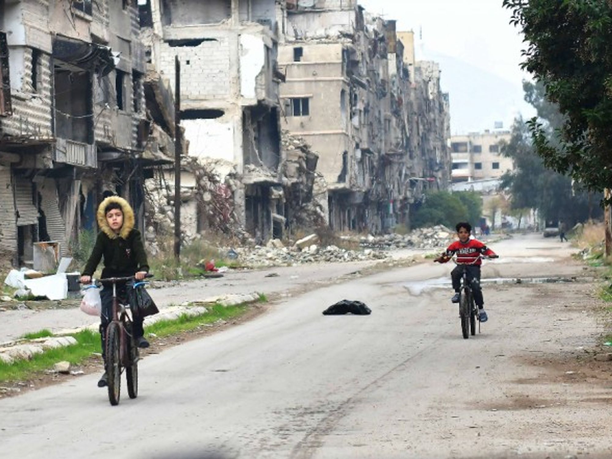 Children ride in the Yarmouk Camp area, south of the capital Damascus