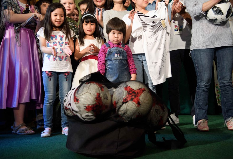 Children stand behind a bag of soccer balls in an orphanage