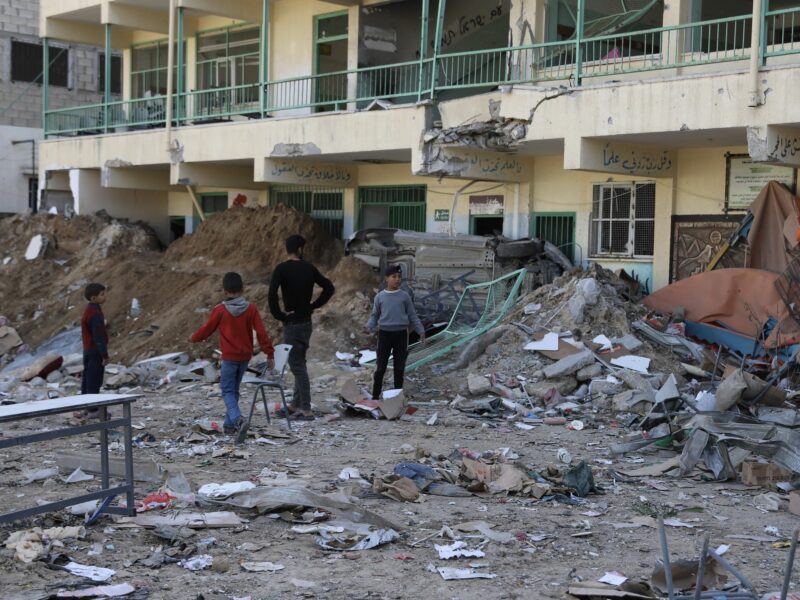 Children stand in front of a damaged school in Gaza City.
