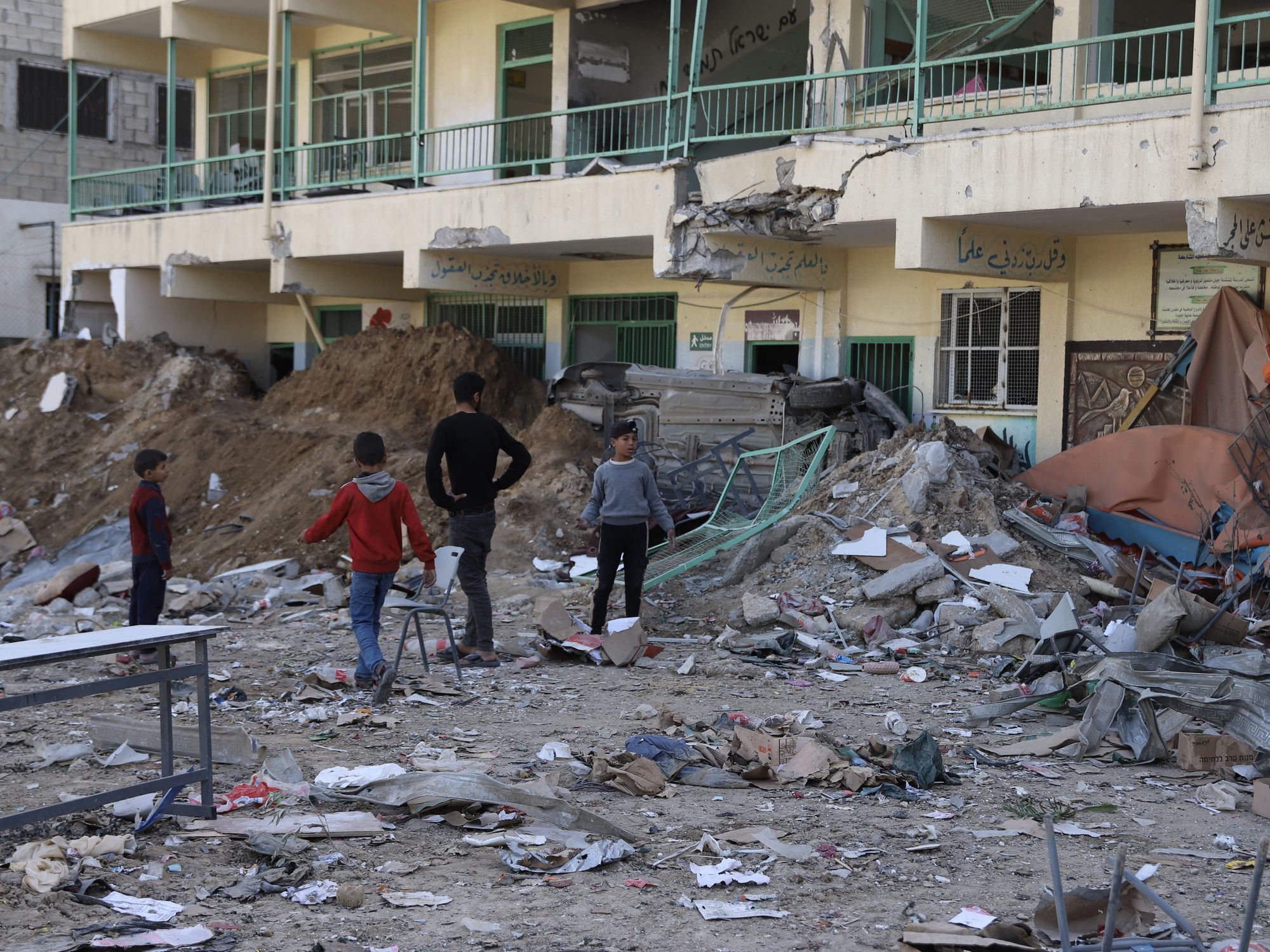Children stand in front of a damaged school in Gaza City.