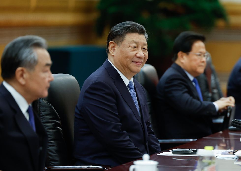 China's President Xi Jinping looking on at a meeting with two men beside him