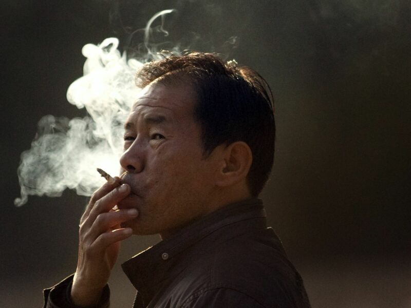 Chinese man smoking a cigarette with a solemn facial expression