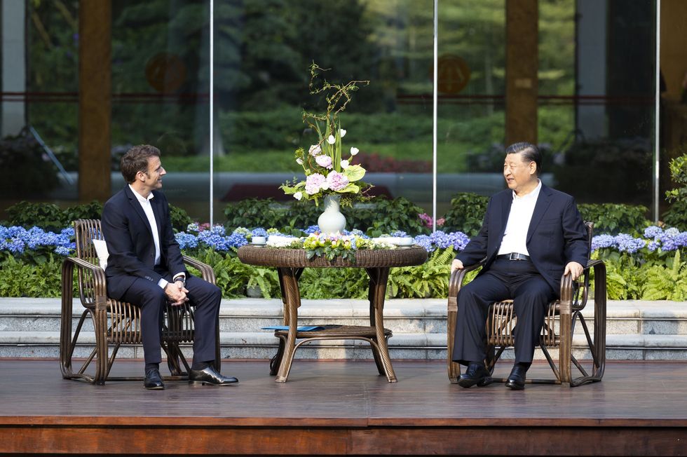 Chinese President Xi Jinping (right) and French President Emmanuel Macron (left) have tea surrounded by flowers