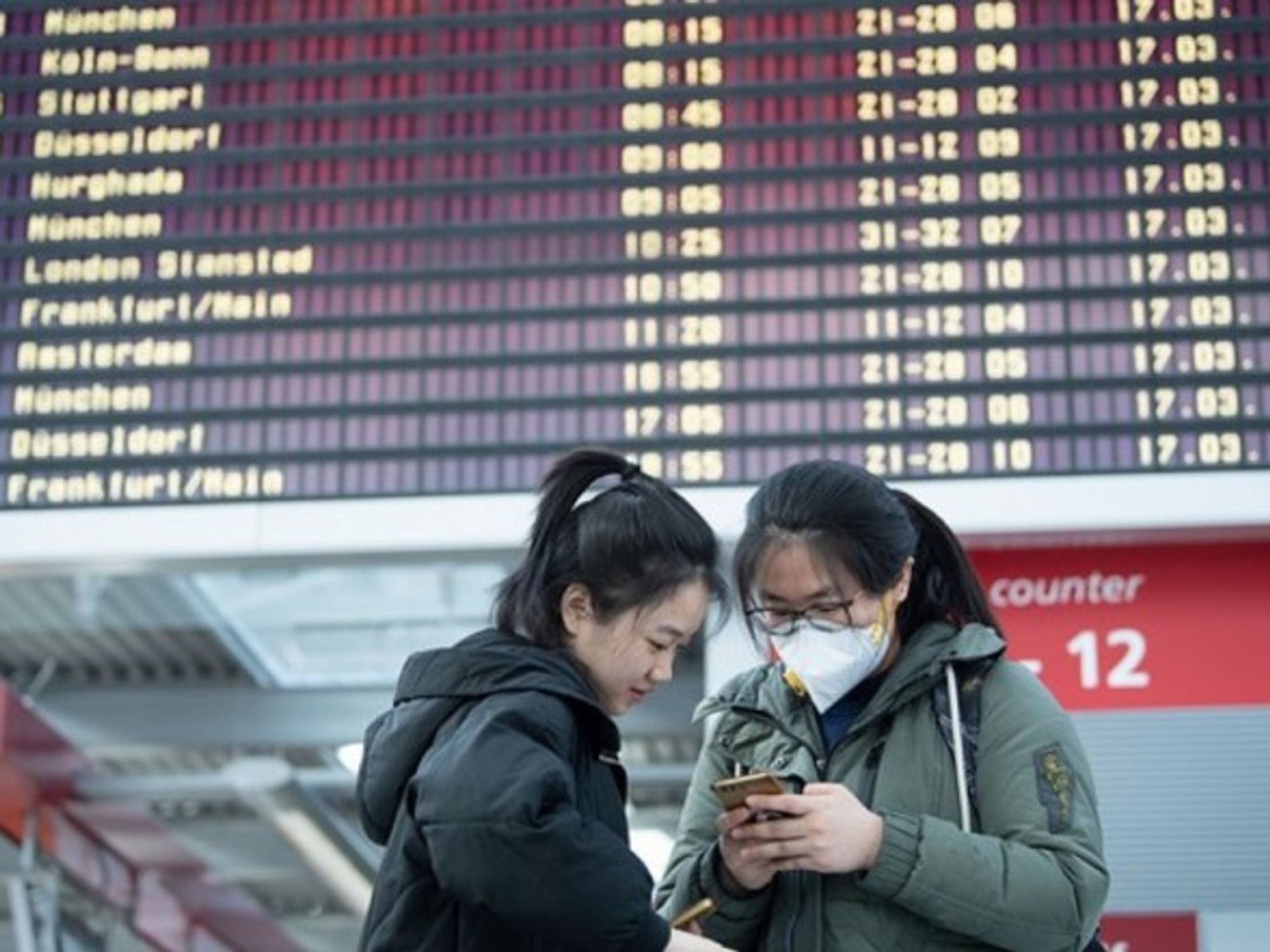 Chinese students in front of a departure board at Dresden Airport, where numerous flights are cancelled due to the coronavirus pandemic.