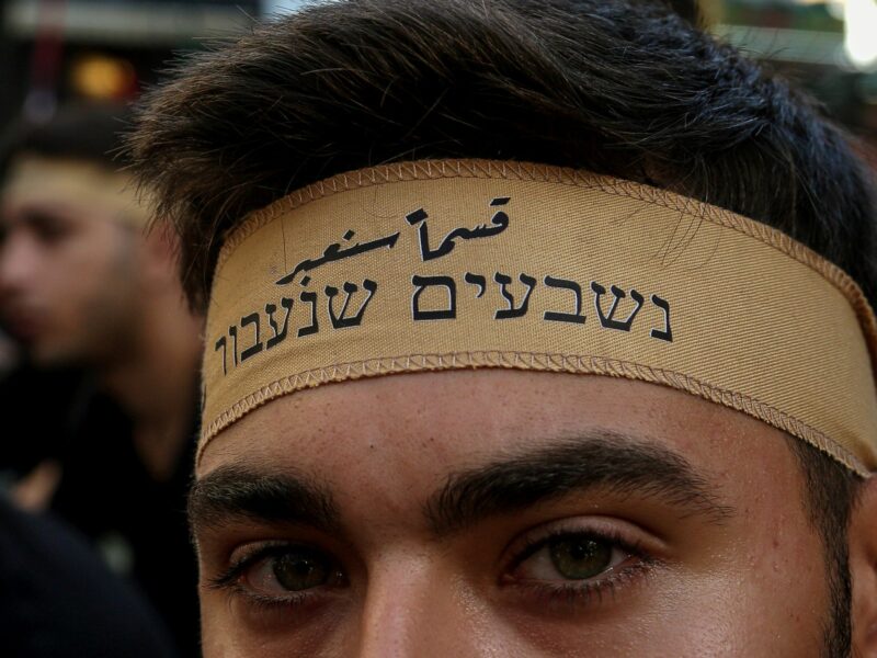 Close-up photo of a Hezbollah supporter sporting a headband that reads in Arabic and Hebrew "We swear we will cross [into Israel]" during a rally in Beirut.