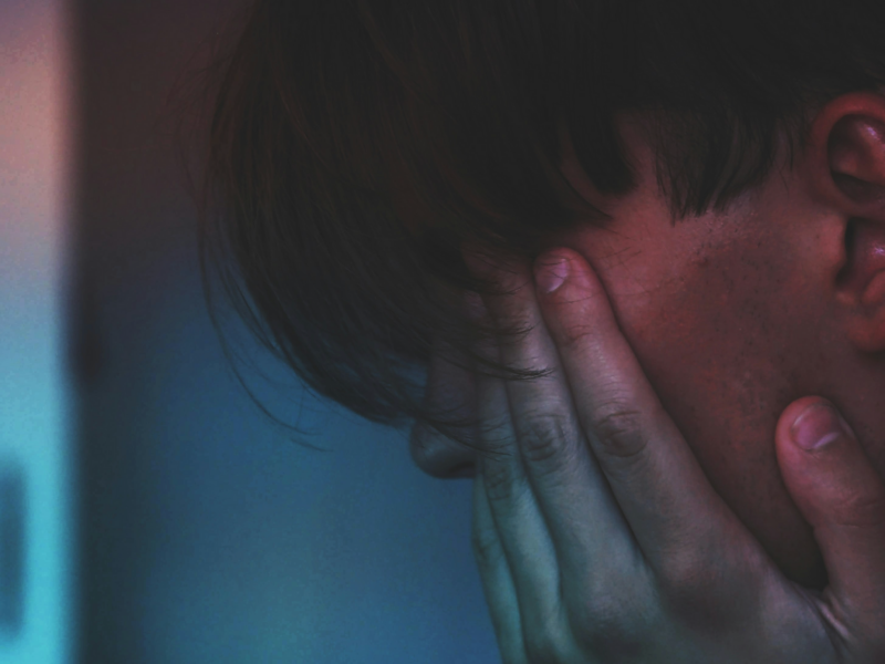 Close-up photo of a young man with his head in his hands