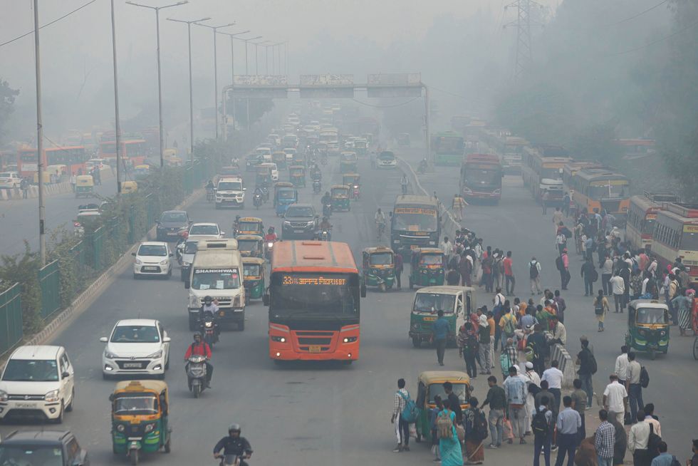 Commuters wait for the bus outside the Anand Vihar bus terminal on a smoggy day amid deteriorating air quality levels.