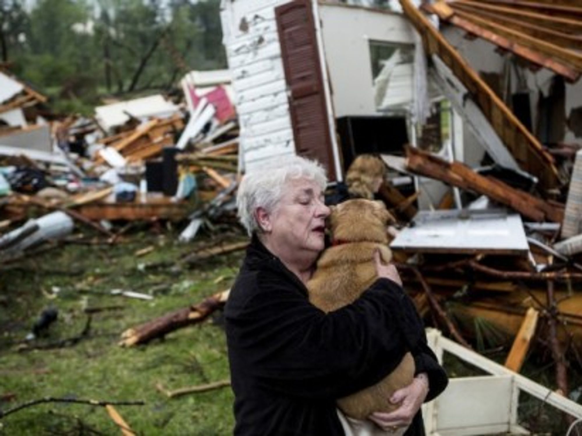Constance Lambert hugs her dog after finding it alive when she returned to her destroyed home.