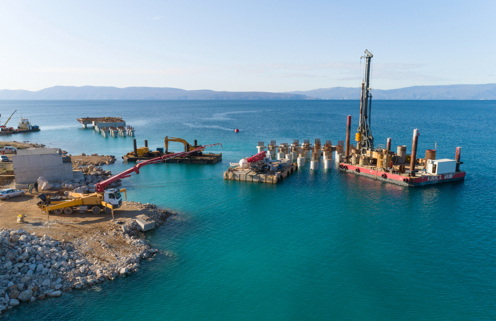 Croatia, November 2019: Aerial view of machinery at the construction of future LNG terminal on the shore of the bay in Omisalj.