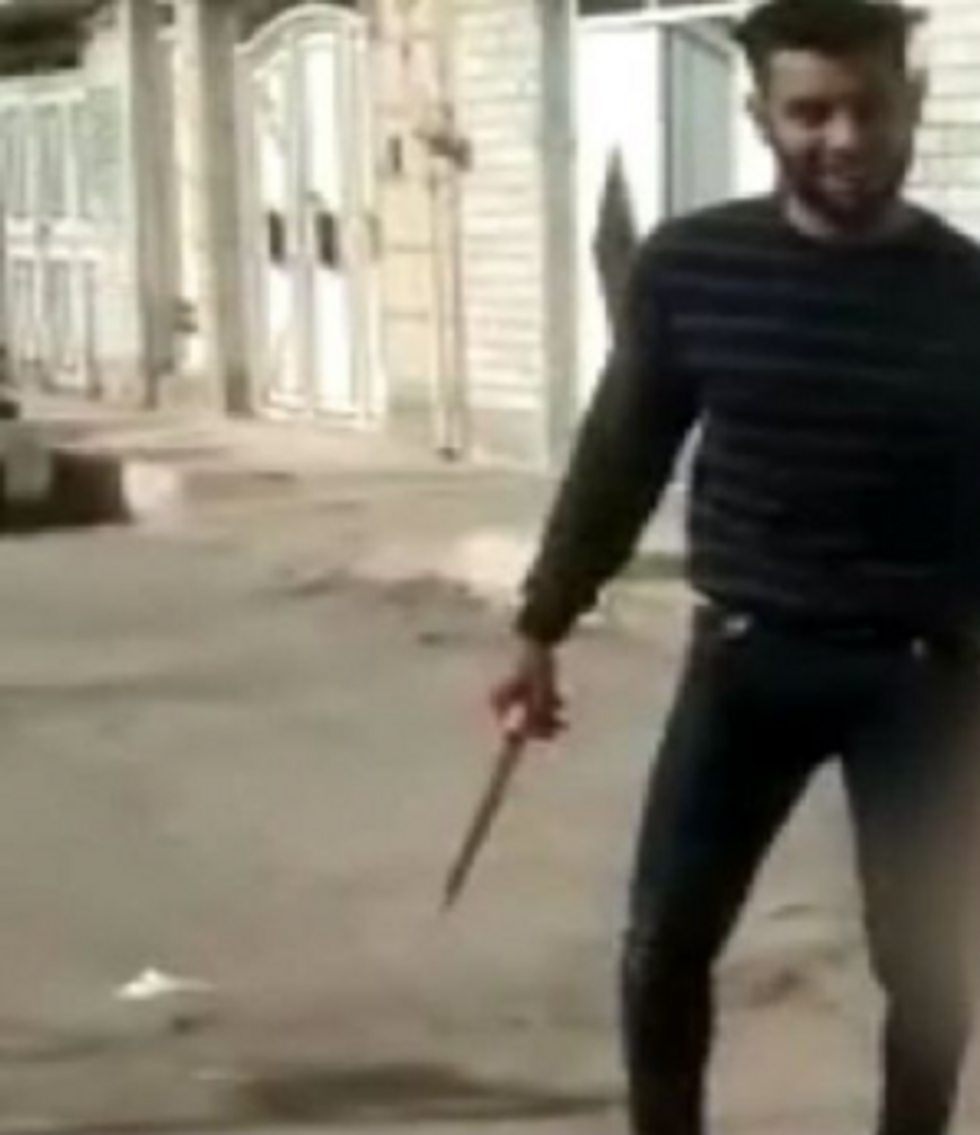 Cropped screenshot of the video showing the man smiling as he parades his wife's head through the streets of Ahvaz