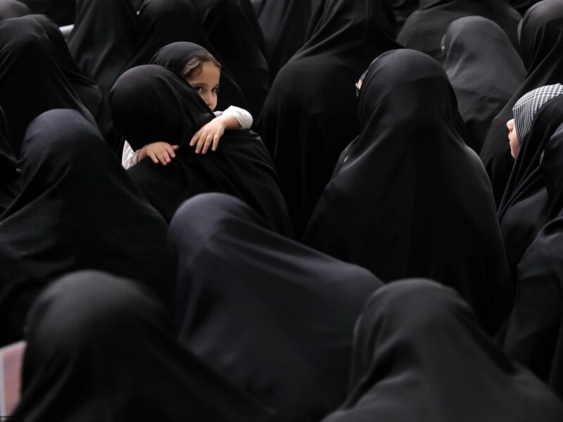 Crowd of women wearing hijab while a small child is being carried also wearing a hijab