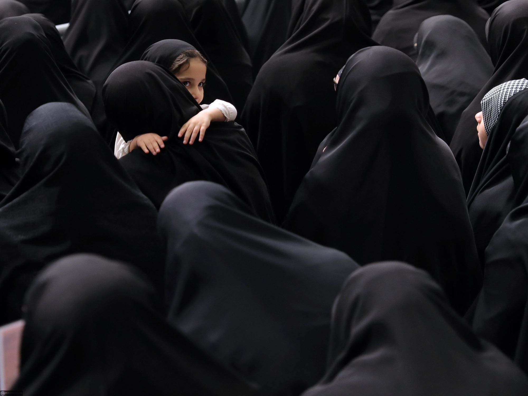 Crowd of women wearing hijab while a small child is being carried also wearing a hijab