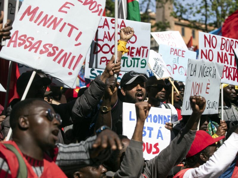 Demonstrators hold up fists and placards in Rome