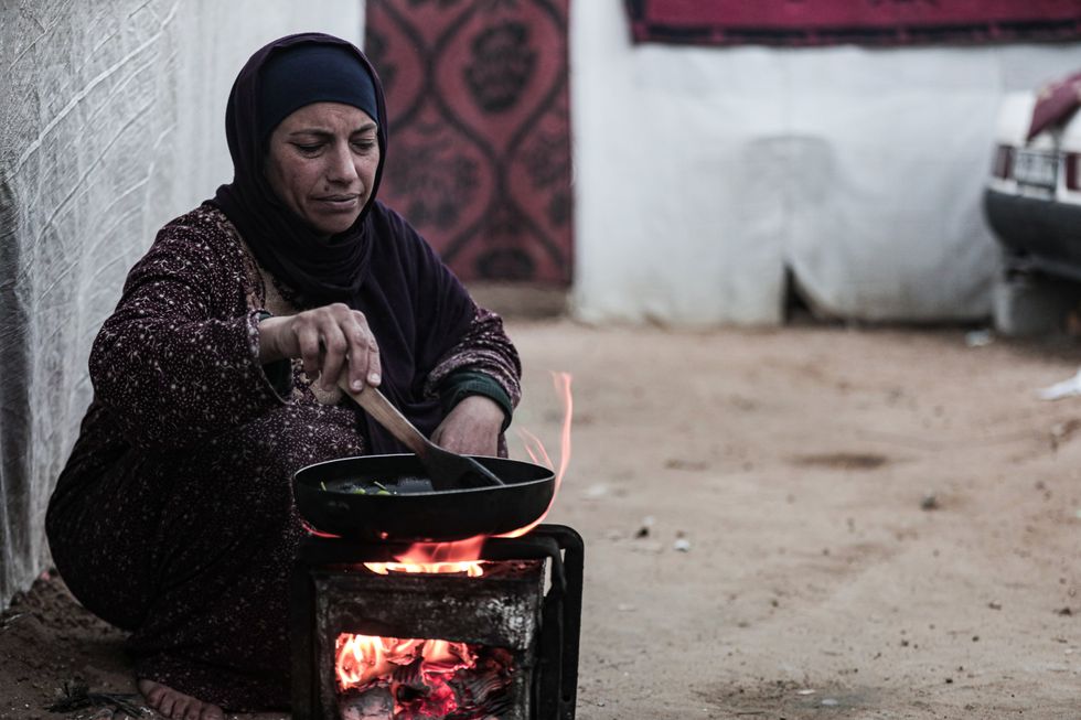 Displaced Palestinians cook very basic food outside their tents around the Shuhada al-Aqsa Hospital in Deir al-Balah, in the middle area of the Gaza Strip.