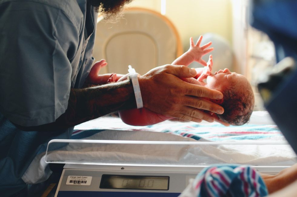 Doctor holding a newborn baby in the delivery room.
